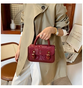 Detail of burgundy snakeskin flap and golden buckles on a vintage handbag