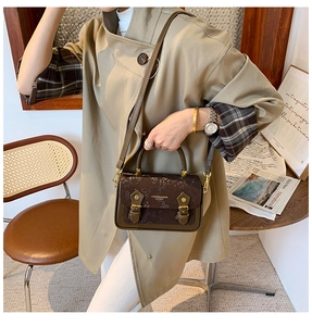 Brown snakeskin crossbody bag detail shown in a lifestyle vintage fashion setting