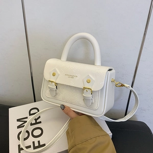 Close-up of white snakeskin texture flap with gold clasp on minimalist box bag