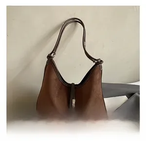 Detail of brown suede hobo bag showing retro stitching and dark leather piping details