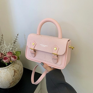Close-up of pink handbag featuring snake-embossed texture and golden metal hardware