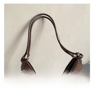 Detail of brown vintage underarm bag featuring suede texture and leather piping accents