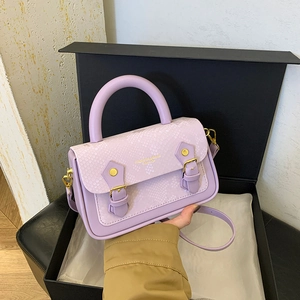 Detail of light purple bag with snakeskin pattern, hard handle, and gold hardware accents