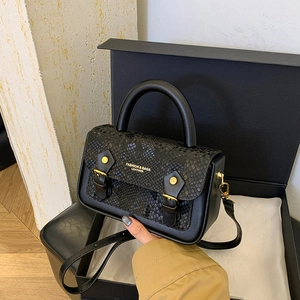 Close-up of black crossbody bag with snakeskin texture and gold buckle details