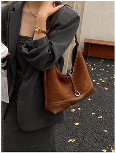 Detail of a brown hobo shoulder bag with white stitching and silver ring buckle