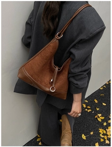 Close-up of brown suede hobo bag with leather trim and silver metal ring detail