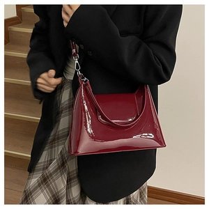 Detail of red patent leather shoulder bag with silver hardware on a fashion model