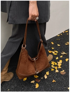 Brown vintage hobo bag in matte suede held by a model wearing a grey wool coat