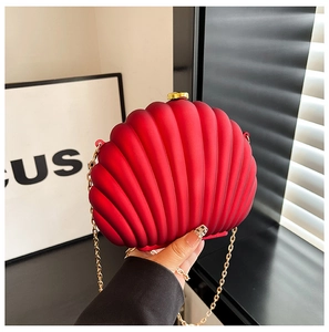 Close-up of red shell-shaped evening bag with golden chain and matte acrylic texture
