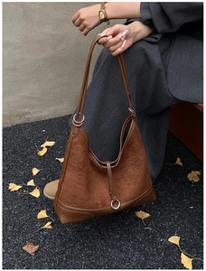 Close-up of vintage brown suede shoulder bag with leather trim and silver metal buckle