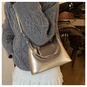 Detail of champagne gold patent leather bag with metallic finish and silver zipper
