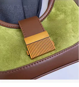 Macro detail of gold striped metal buckle on green suede and brown leather bag
