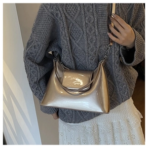 Detail of champagne gold metallic crossbody bag shown on a model with knit sweater