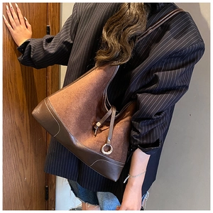 Detail of vintage brown suede shoulder bag with leather drawstring and metal buckle ring