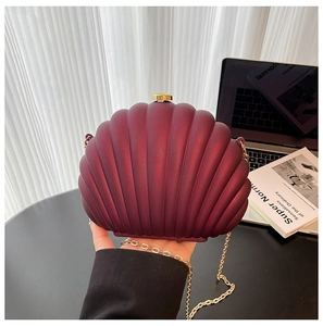 Detail of burgundy shell-shaped clutch with matte texture and golden chain strap