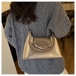Detail of champagne gold patent leather crossbody bag showing glossy texture and strap