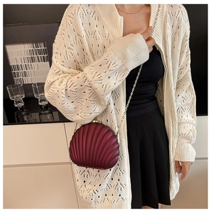 Detail of shell-shaped wine red acrylic bag with shell texture and gold chain strap