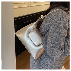 Detailed shot of silver pearl finish leather shoulder bag on grey knitted sweater
