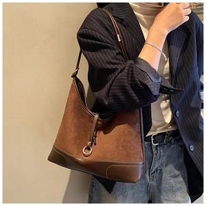 Detailed close-up of brown suede and leather patchwork underarm bag with metal ring