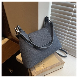 Detail of blue-grey denim shoulder bag with silver hardware and durable fabric texture