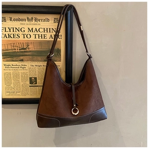 Detail of vintage brown suede shoulder bag with retro metal ring buckle and leather strap