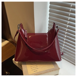 Detail of burgundy patent leather handbag with glossy finish and silver metal hardware