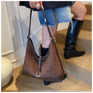 Close-up of vintage brown suede shoulder bag with leather trim and gold ring detail