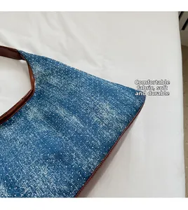 Detail of blue denim tote bag featuring white rhinestones and brown leather trim