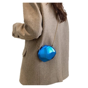 Blue metallic crossbody bag with gold chain strap shown on model in wool coat