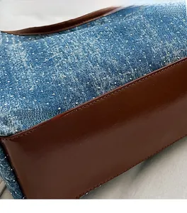 Detailed shot of blue denim tote with silver rhinestones and brown leather stitching
