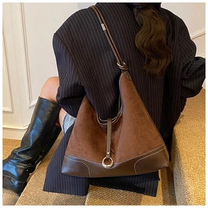 Detail of vintage brown suede hobo bag with contrast stitching and metal ring buckle