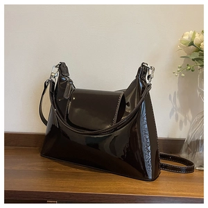 Detail of dark brown patent leather shoulder bag with glossy finish and silver buckle hardware