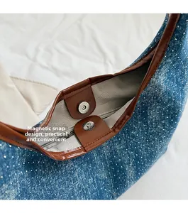 Detail of blue denim tote bag featuring white polka dots and secure magnetic buckle closure