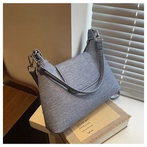 Detail of blue denim shoulder bag with silver hardware on vintage books and wood surface