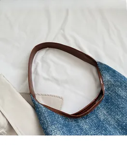 Detail of blue denim tote bag with white polka dots and premium brown leather shoulder strap