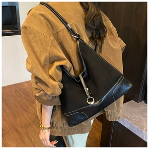Detailed view of a black leather tote bag with silver ring and contrast stitching details