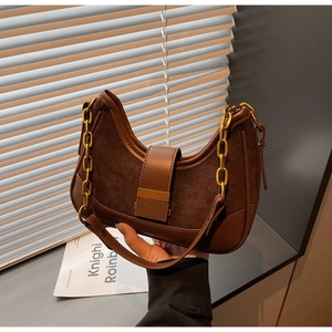 Detail of dark brown suede shoulder bag featuring gold chain and retro metal clasp