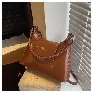 Close-up of caramel glossy patent leather shoulder bag with sleek flap and fine strap detail
