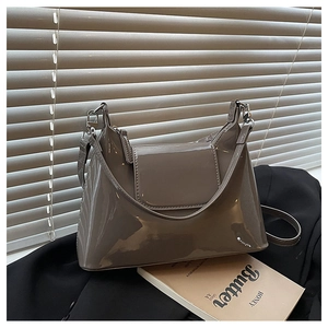 Chic mocha grey patent leather shoulder bag with silver hardware on a black blazer