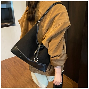 Detail of black tote bag featuring white contrast stitching and metallic ring decor
