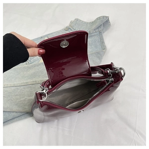Detail of burgundy patent leather bag interior with silver magnetic buckle and zipper pocket