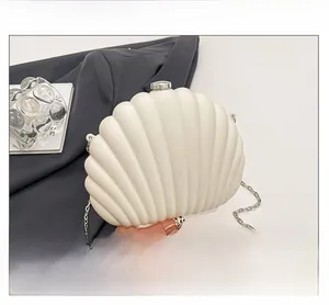 Detail of white shell-shaped evening clutch featuring acrylic texture and silver chain