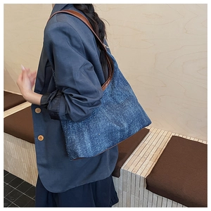 Detail of blue glitter denim tote bag with brown leather strap worn over the shoulder