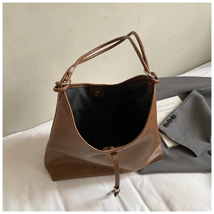 Top-down view of brown leather tote bag with black lining and magnetic snap closure