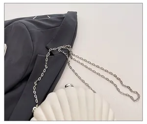 Detail of a white shell-shaped evening bag with a premium silver metal chain strap