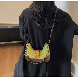 Detail of olive green suede crescent bag with brown leather trim and metal chain strap