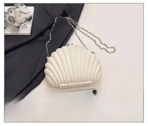 Detail of shell shaped crossbody bag with metal chain and phone for size reference