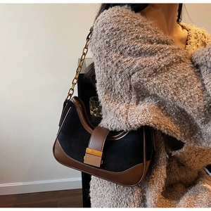 Detail of suede half-moon bag with gold chain strap on a cream knit sweater