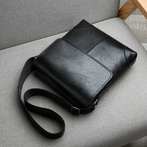 Detail of black crossbody bag with litchi grain texture and adjustable nylon shoulder strap