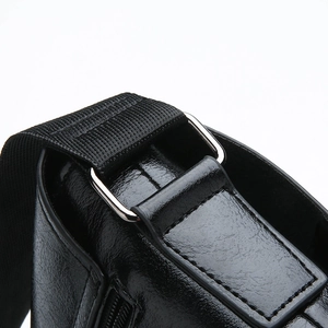 Detail of silver D-ring buckle on black leather shoulder bag with textured fabric strap